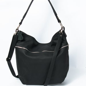 May include: A black nylon shoulder bag with a silver zipper and a long adjustable strap.
