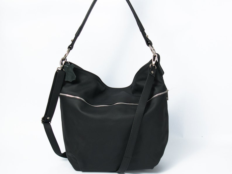 May include: A black nylon shoulder bag with a silver zipper and a long adjustable strap.
