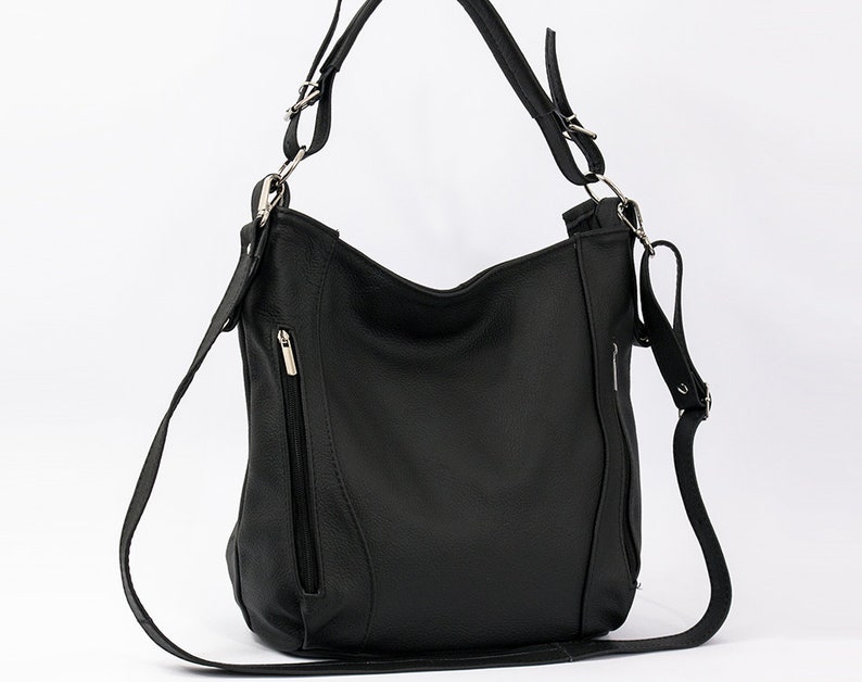 May include: A black leather shoulder bag with a long strap and silver hardware. The bag has a zippered pocket on the front.