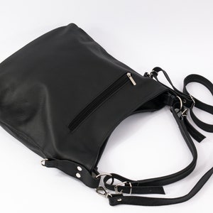 May include: Black leather shoulder bag with a zippered pocket and adjustable straps.