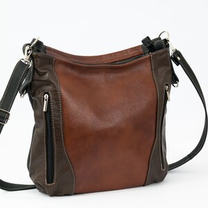 Pode incluir: Uma bolsa de ombro de couro marrom e preto com um bolso com z&iacute;per na frente. A bolsa tem uma al&ccedil;a longa ajust&aacute;vel.