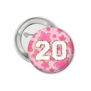 May include: A pink button with a white number "20" surrounded by pink glitter stars.