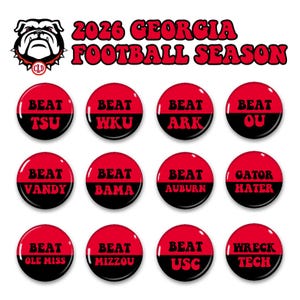 May include: A collection of twelve circular buttons featuring a red and black split design. The text 2026 GEORGIA FOOTBALL SEASON appears at the top with a bulldog mascot logo. Each button displays phrases like BEAT TSU, BEAT WKU, BEAT ARK, BEAT OU, BEAT VANDY, BEAT BAMA, BEAT AUBURN, GATOR HATER, BEAT OLE MISS, BEAT MIZZOU, BEAT USC, and WRECK TECH.