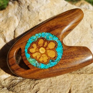 May include: A wooden carving in the shape of a flower with turquoise inlay. The carving is made of dark wood and has a smooth finish.