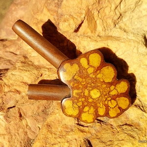 May include: A wooden smoking pipe with two stems and a yellow and brown resin bowl. The bowl has a unique marbled design.