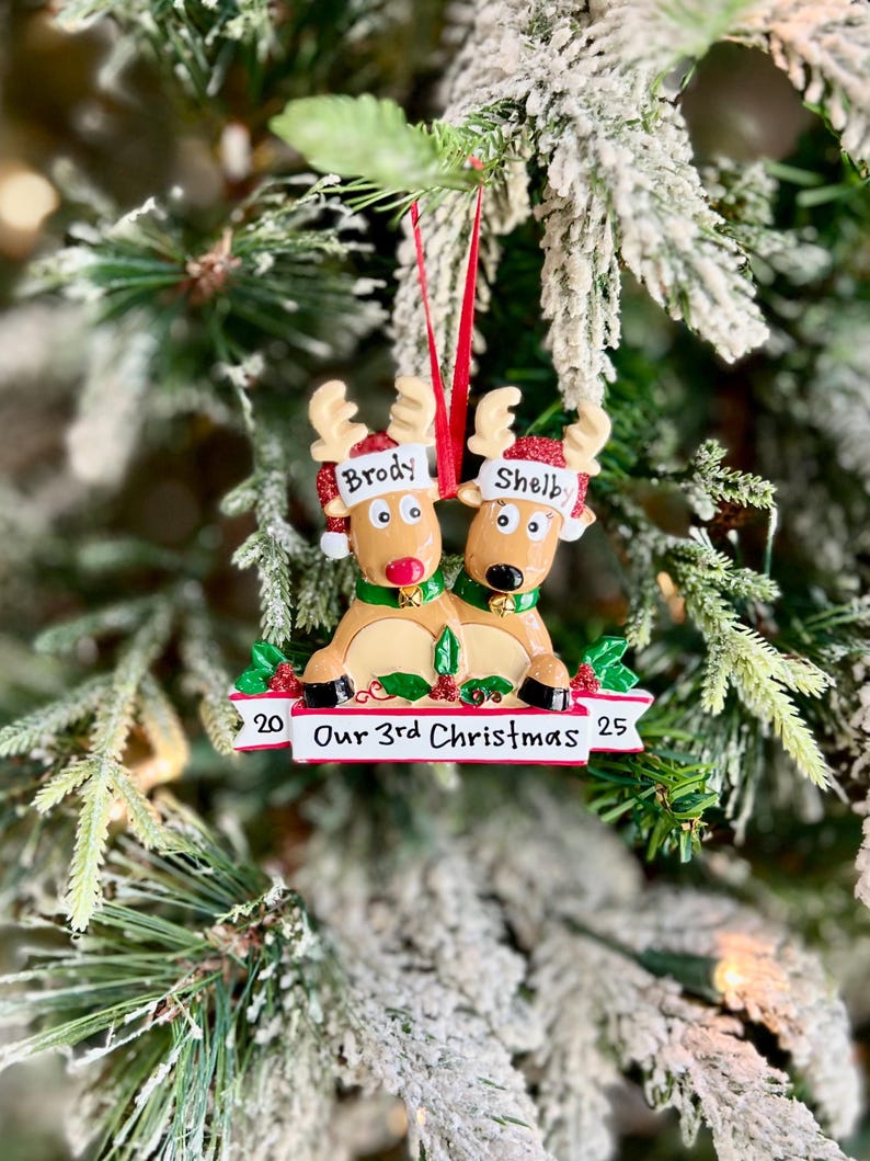 May include: A Christmas ornament featuring two reindeer with the names "Brody" and "Shelby" on their hats. The ornament reads "Our 3rd Christmas" with the year 2025. The ornament is decorated with red, green, and gold accents.