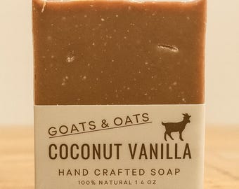 May include: A rectangular bar of brown soap with a white label. The label reads "Goats & Oats Coconut Vanilla Hand Crafted Soap 100% Natural 14 oz" with a goat silhouette.