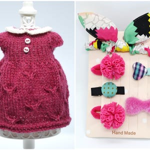 May include: A magenta knitted dress with a white collar and two white buttons. Beside it is a display of hair accessories, including a bow, pom-pom clips, and a patterned headband with bunny ears. The card reads "Hand Made."