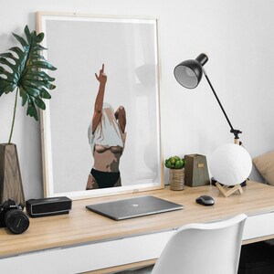 May include: A framed illustration of a person with their arm raised in the air, making a middle finger gesture. The person is wearing a white shirt and black underwear. The illustration is on a light gray background.