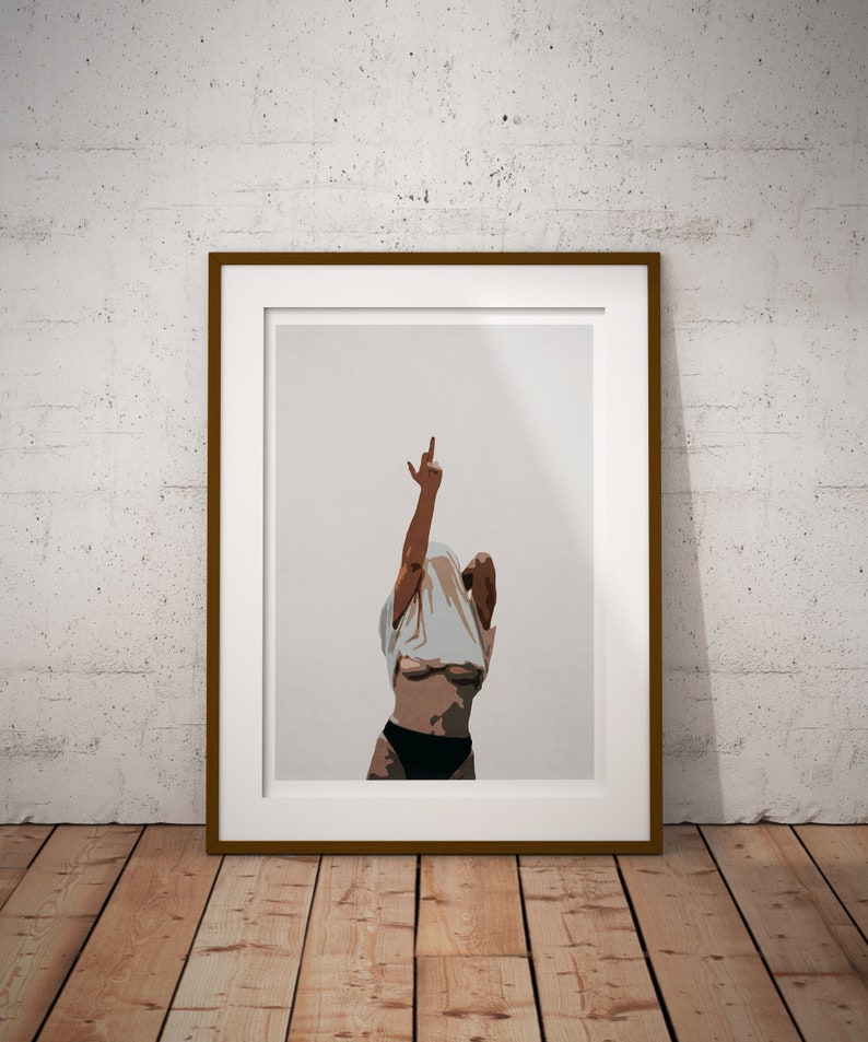 May include: A framed print of a woman in a white t-shirt, with her arms raised and one hand making a peace sign. The background is a light gray.