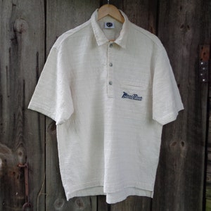 May include: A white short-sleeved polo shirt with a blue embroidered logo that says "Maui Blue" and "Enriched Tournament".
