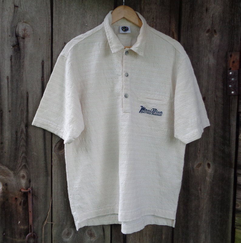 May include: A white short-sleeved polo shirt with a blue embroidered logo that says "Maui Blue" and "Enriched Tournament".
