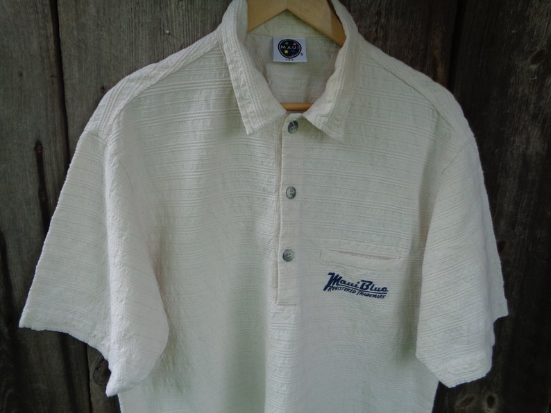 May include: A white short-sleeved polo shirt with a blue embroidered logo that says "Maui Blue" and "Registered Trademark".