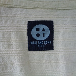 May include: A black label with a white circle, square, and triangle inside. The label says "Maui and Sons" and "Blue" in white text.