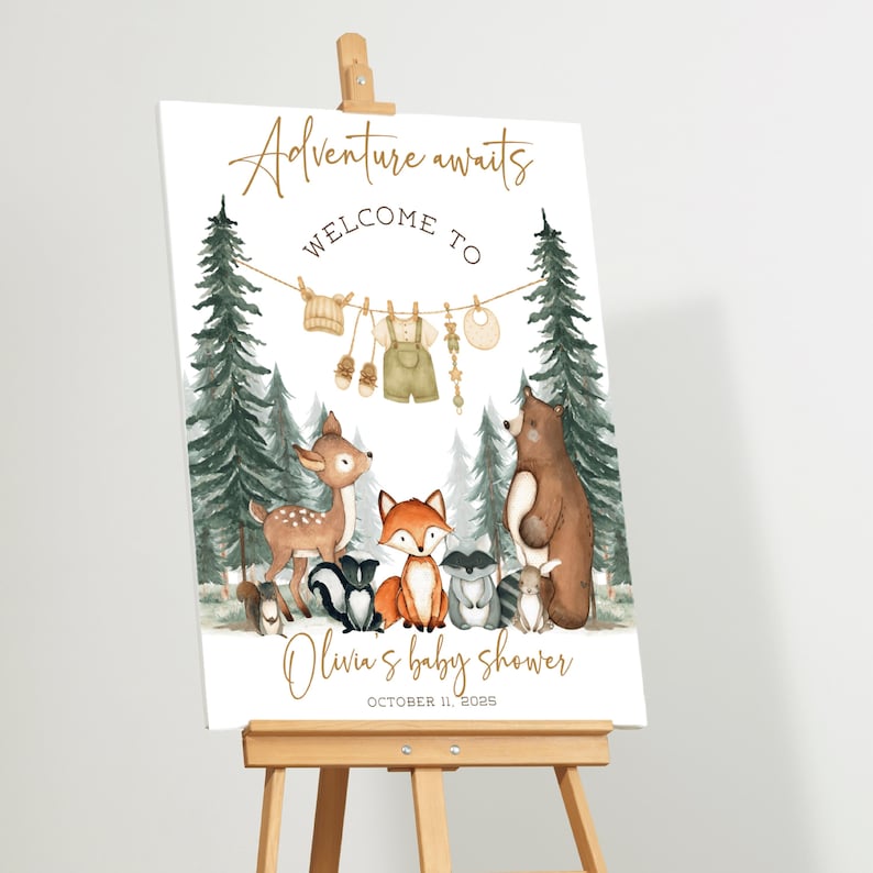 May include: A welcome sign on an easel with the text "Adventure awaits" and "Welcome to" above a watercolor illustration of forest animals. The sign is for Olivia's baby shower, October 11, 2025.
