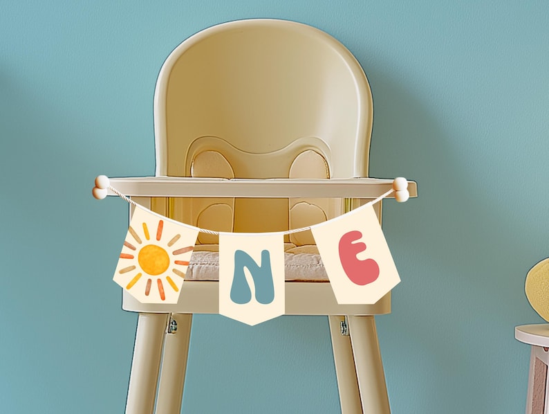 High chair banner spelling out “ONE” with bright sun artwork and bold playful fonts, perfect for first birthday smash cake photo setup.