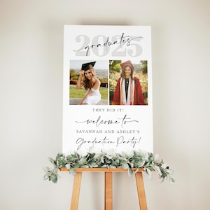 Graduation poster with dual photo design and minimal script typography on a wooden easel with a greenery accent. Text reads “They Did It! Welcome to Savannah and Ashley’s Graduation Party,” placed beneath the bold “2025” and “graduates” script. An editable and printable Canva template suited for modern dual grad celebrations.
