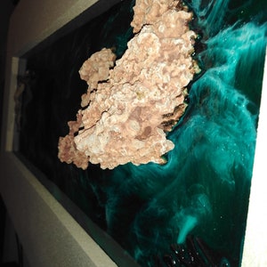 May include: A rectangular resin art piece featuring a coral-like structure in shades of brown and tan, set against a swirling background of deep teal and black. The artwork is framed in a light-colored border.