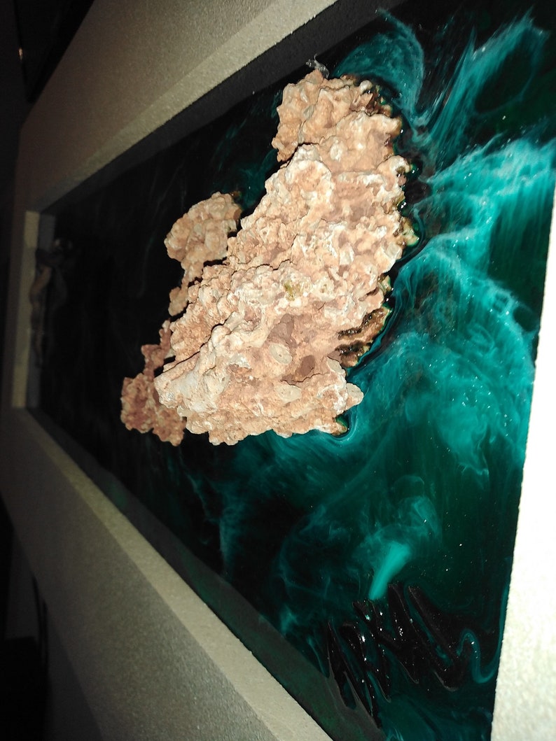 May include: A rectangular resin art piece featuring a coral-like structure in shades of brown and tan, set against a swirling background of deep teal and black. The artwork is framed in a light-colored border.