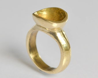 Puede incluir: Un anillo de oro con un diseño único en forma de lágrima. El anillo está hecho de metal sólido y tiene un acabado liso y pulido.