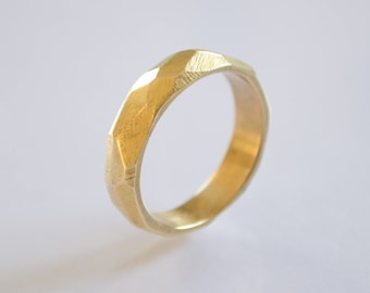 May include: A gold ring with a geometric, faceted design. The ring is made of a smooth, polished metal.