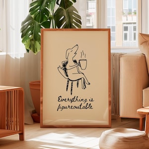 May include: A framed print with a cartoon dog illustration in black and white, seated and holding a coffee cup. The text "Everything is figureoutable" is below the dog. The frame is a light brown colour.