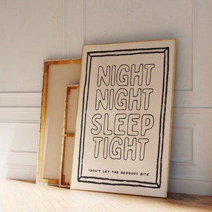 以下が含まれることがあります： 白いキャンバスに黒い文字で「Night Night Sleep Tight」と「Don't Let The Bedbugs Bite」と書かれたプリント。プリントは金色のフレームで囲まれ、白い壁に立てかけられている。