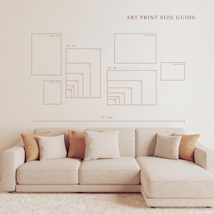 May include: An art print size guide is displayed on a beige wall above a beige sectional sofa with throw pillows. The guide shows various rectangular shapes with size labels. The sofa is on a white rug.