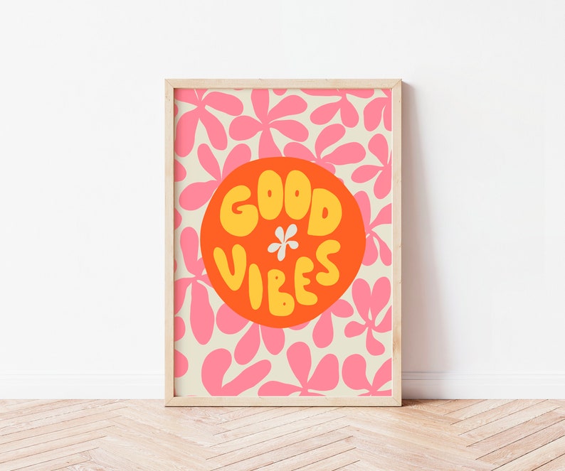 May include: A framed print with a pink and white floral pattern. The print features a large orange circle with the text "GOOD VIBES" in yellow letters.