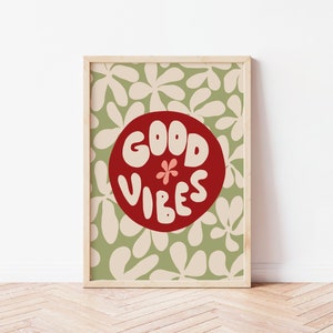 May include: A framed print with a green and white floral pattern background. A red circle with the text "GOOD VIBES" in white is in the center of the print.