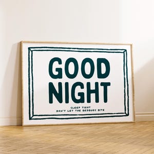 May include: A framed print with a white background and a black frame. The print features the text "GOOD NIGHT" in large, bold, dark blue letters. Below the text is the phrase "SLEEP TIGHT DON'T LET THE BEDBUGS BITE" in smaller, dark blue letters.