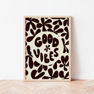 May include: A framed print with a white background and black floral pattern. The print features a circle with the text "GOOD VIBES" in a stylized font.