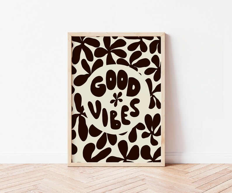 May include: A framed print with a white background and black floral pattern. The print features a circle with the text "GOOD VIBES" in a stylized font.
