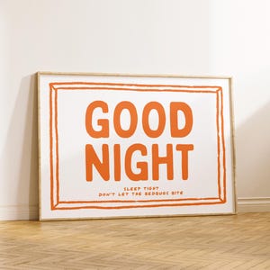 May include: A framed print with a white background and a bold orange text that reads "GOOD NIGHT" with the smaller text "SLEEP TIGHT DON'T LET THE BEDBUGS BITE" underneath.