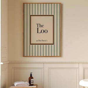 Framed personalised “The Loo” bathroom sign with sage green stripes hanging above a bathroom vanity