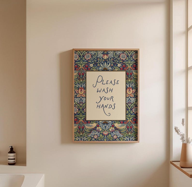 May include: Framed wall art with a floral border in blue, red, and yellow. The centre has the text "Please Wash Your Hands" in script on a cream background. The frame is light brown. Ideal for a bathroom or washroom.