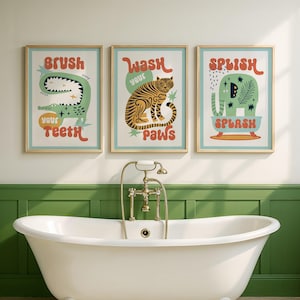 May include: Three framed art prints with animal illustrations and text. The prints feature a green alligator with the text "Brush Your Teeth", a tiger with "Wash Your Paws", and an elephant with "Splish Splash". The frames are light brown.