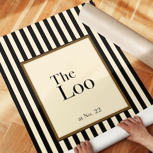 Close-up detail of classic striped “The Loo” wall art showing bold vertical black and cream stripes and elegant serif typography.