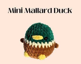 May include: A small, crocheted plush toy duck with green, brown, white, and yellow yarn. The duck has black eyes and a yellow beak.