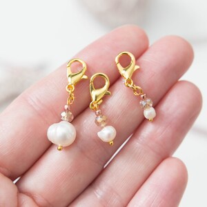 Puede incluir: Tres cierres de metal dorado con un dije de perla y cristal. Cada cierre tiene un cierre de resorte.