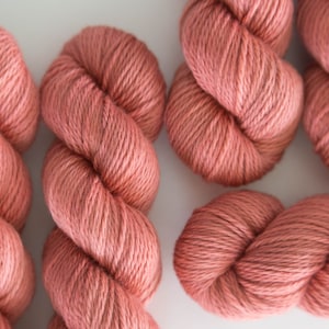 May include: Five skeins of soft, coral-colored yarn, each wound into a ball.