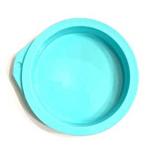 May include: A round, light blue silicone mold with a raised edge and a small tab on the side. The mold is designed for creating round objects and is set against a white background.
