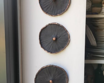 May include: Three black circular wall decorations with a raised centre and a copper rim.