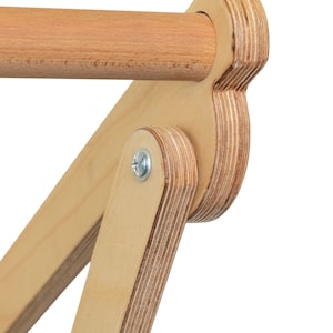 May include: Close-up of a wooden pull-up bar with a rounded, plywood end cap. The bar is attached to a plywood frame with a metal screw.