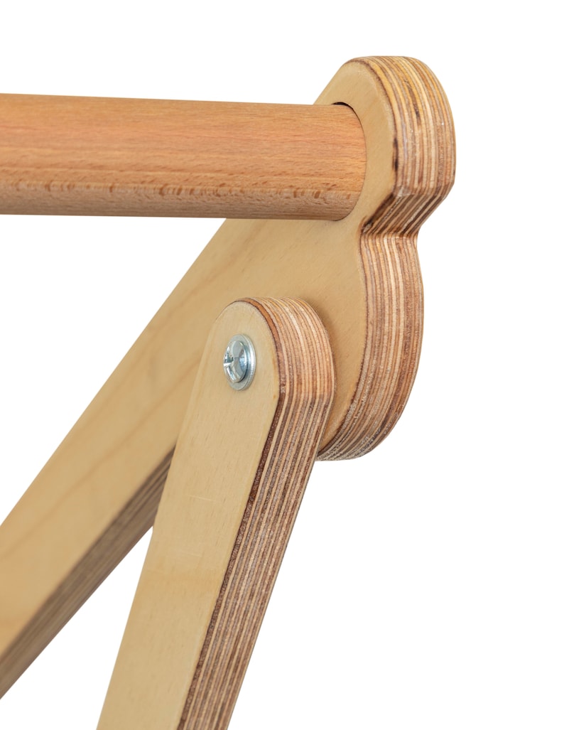 May include: Close-up of a wooden pull-up bar with a rounded, plywood end cap. The bar is attached to a plywood frame with a metal screw.