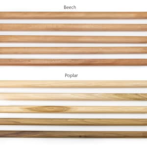 May include: Close-up of wooden dowels in two different wood types: beech and poplar. The beech dowels are a light brown color, while the poplar dowels are a lighter, more yellowish brown.