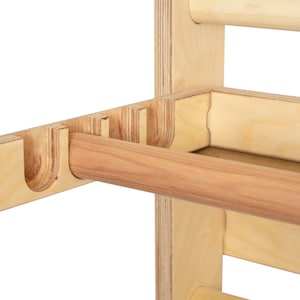 May include: Close-up of a wooden wall-mounted towel rack with a wooden dowel rod. The rack has multiple slots for hanging towels.