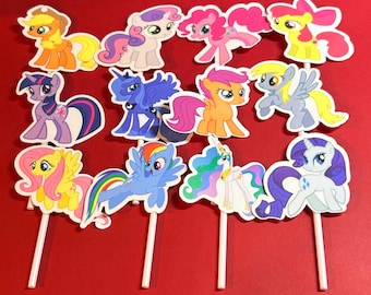 Puede incluir: Una colección de adornos para cupcakes con temática de ponis de colores sobre palitos blancos. Los adornos presentan varios ponis de dibujos animados en tonos de rosa, amarillo, azul, morado y naranja. El fondo es de color rojo liso.