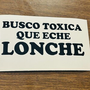 May include: White sticker with black text that reads "BUSCO TOXICA QUE ECHE LONCHE".