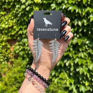 May include: Silver fern leaf earrings with a black card that says "ravenstone" and a raven silhouette.